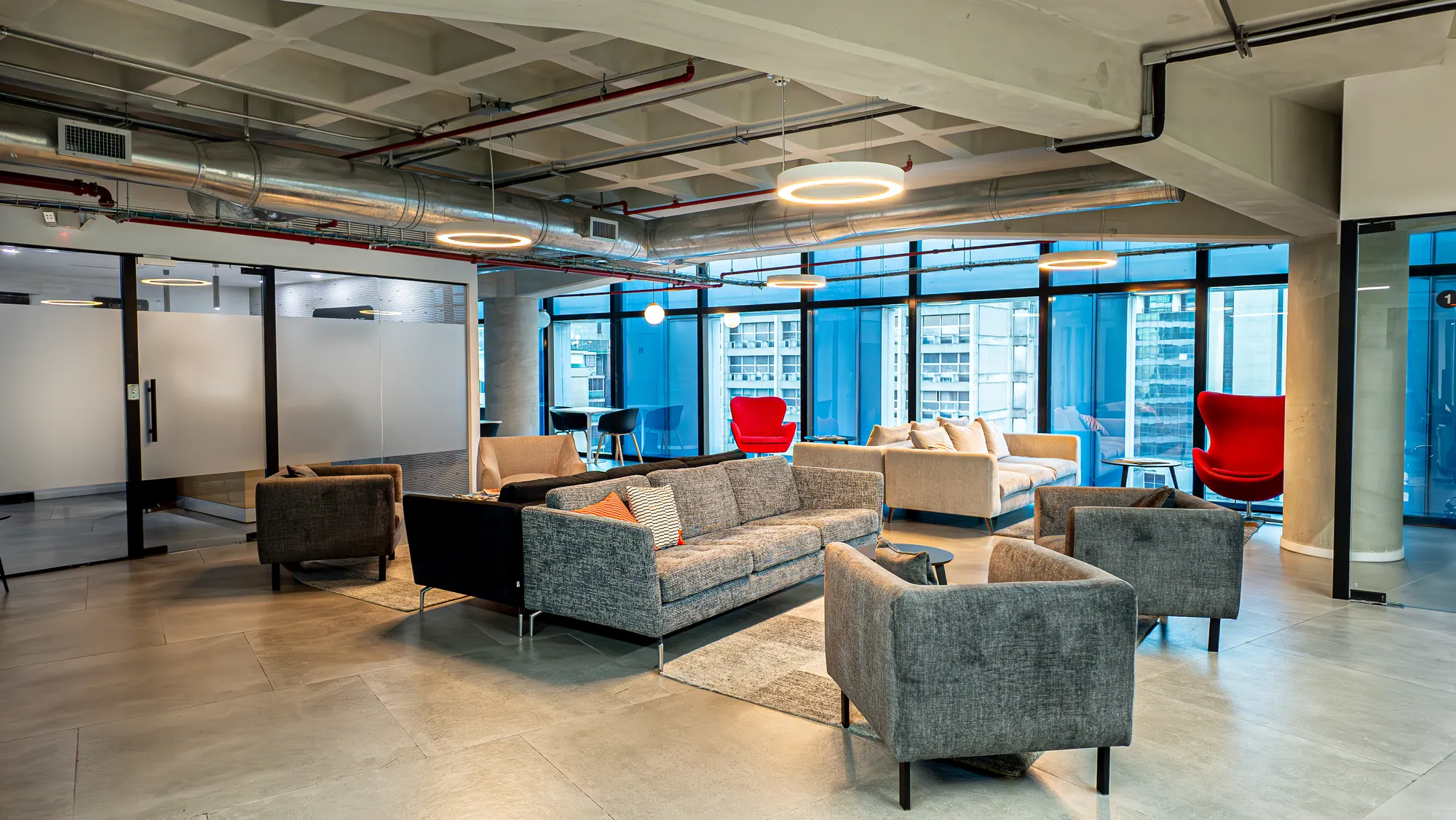 El área común del coworking: sofás y ventanales sobre la avenida
